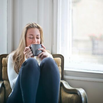 Frau entspannt sich mit einer Tasse Tess auf dem Sessel